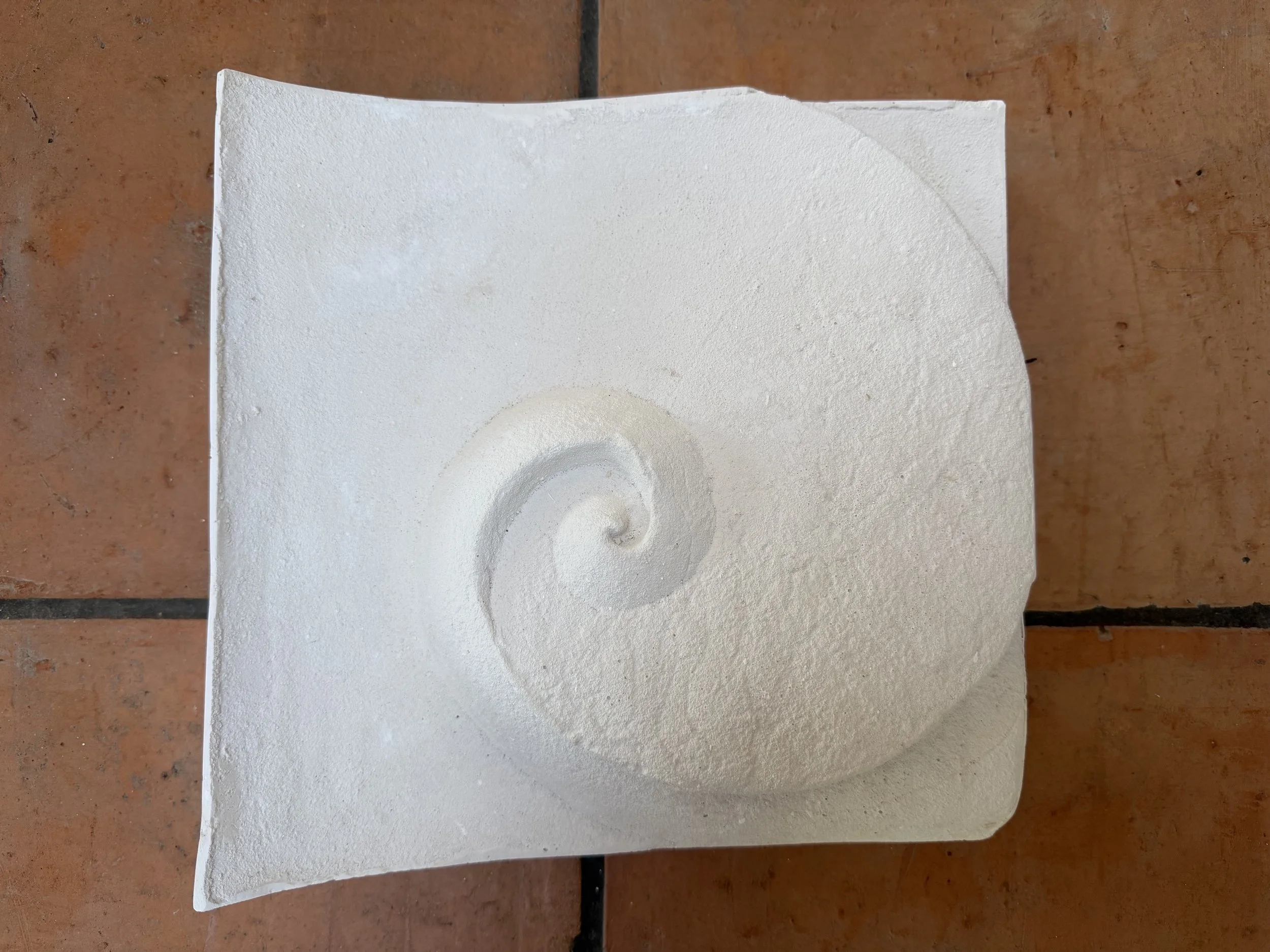 White Moonphase 1 panel displayed on terracotta tiles, with a raised spiral.