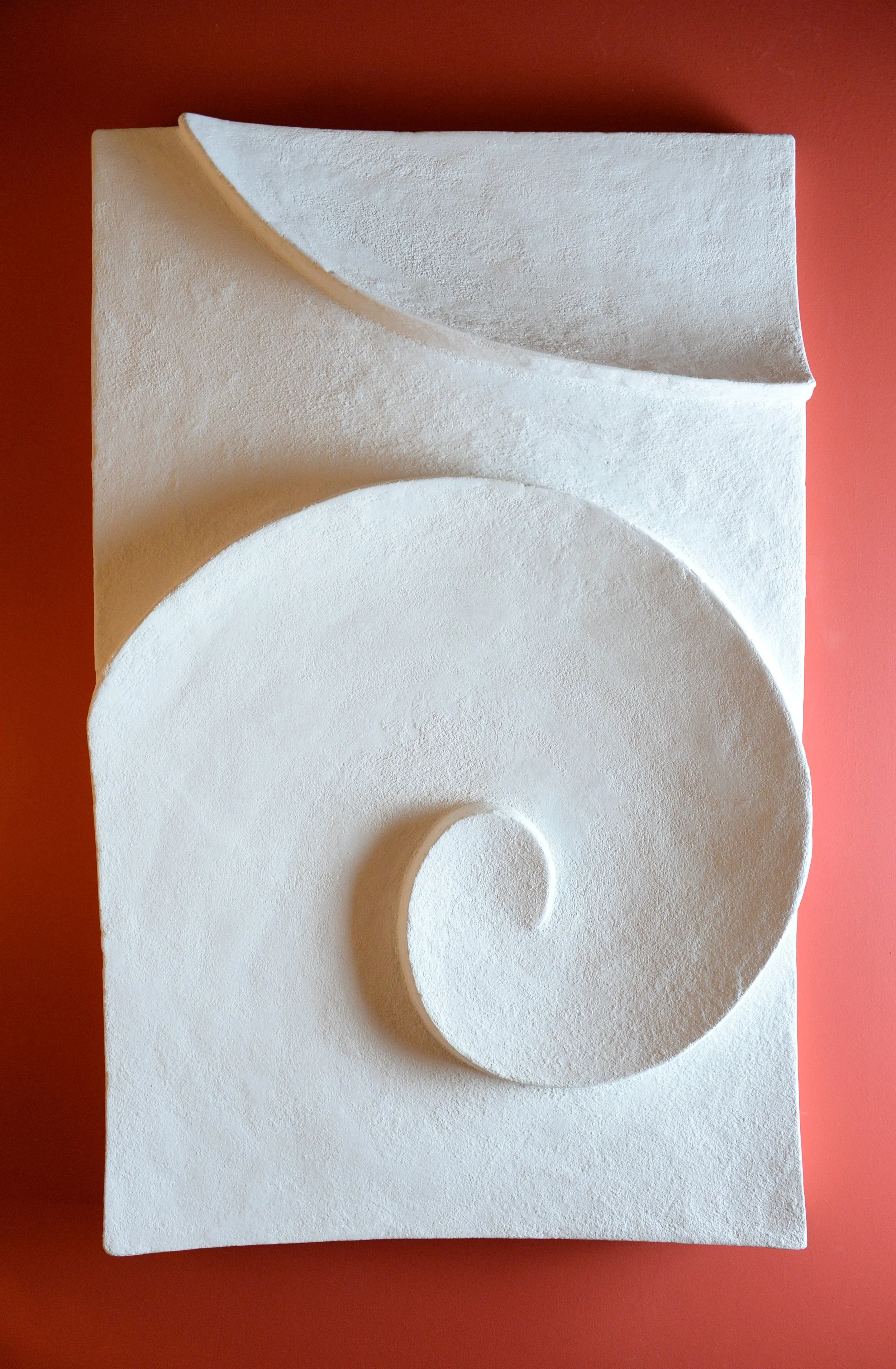 White Moonwave relief arranged vertically against a red background, with opposing curves and a small curl.