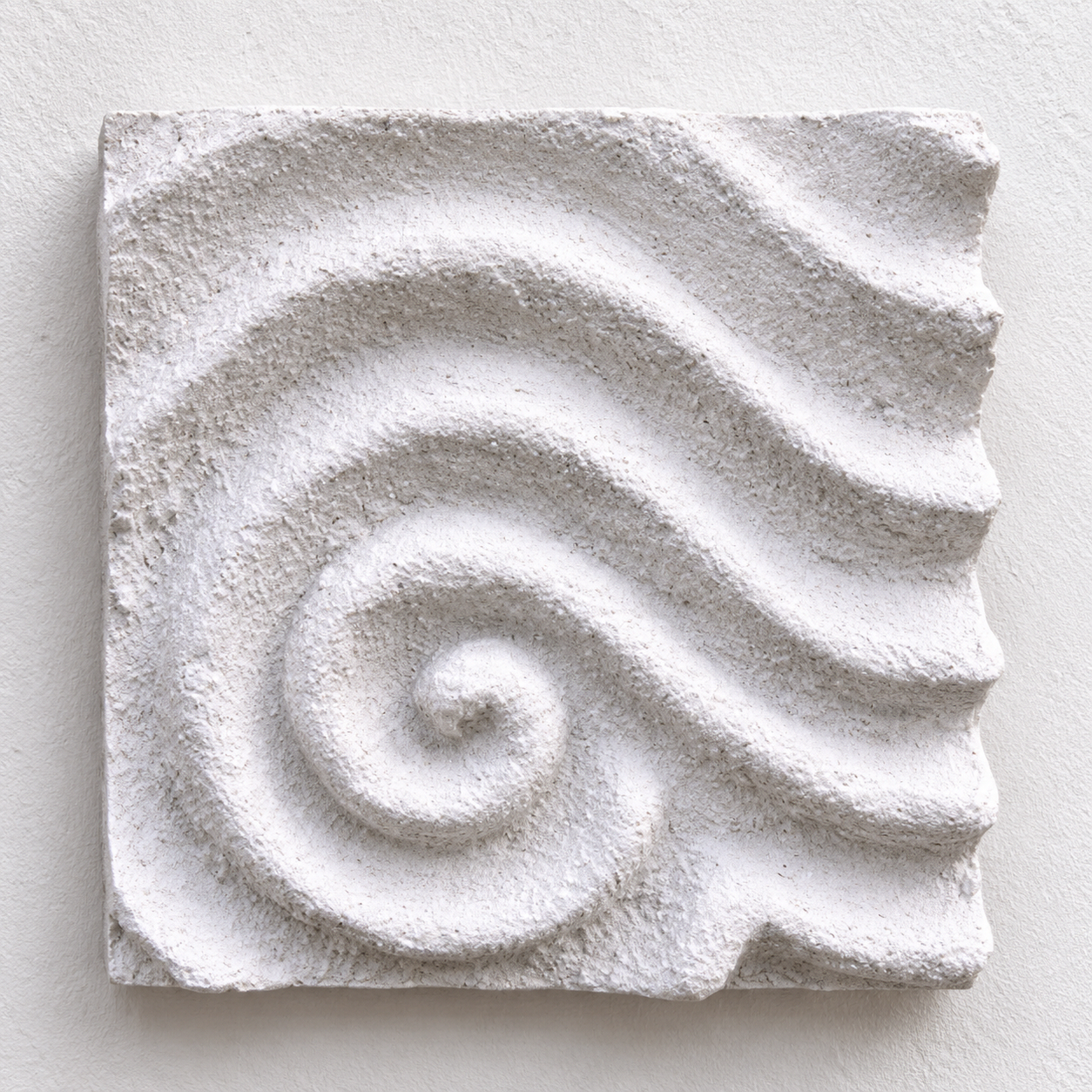 White Raked Spiral 1 relief with textured ridges curling at the lower left, against a pale background.