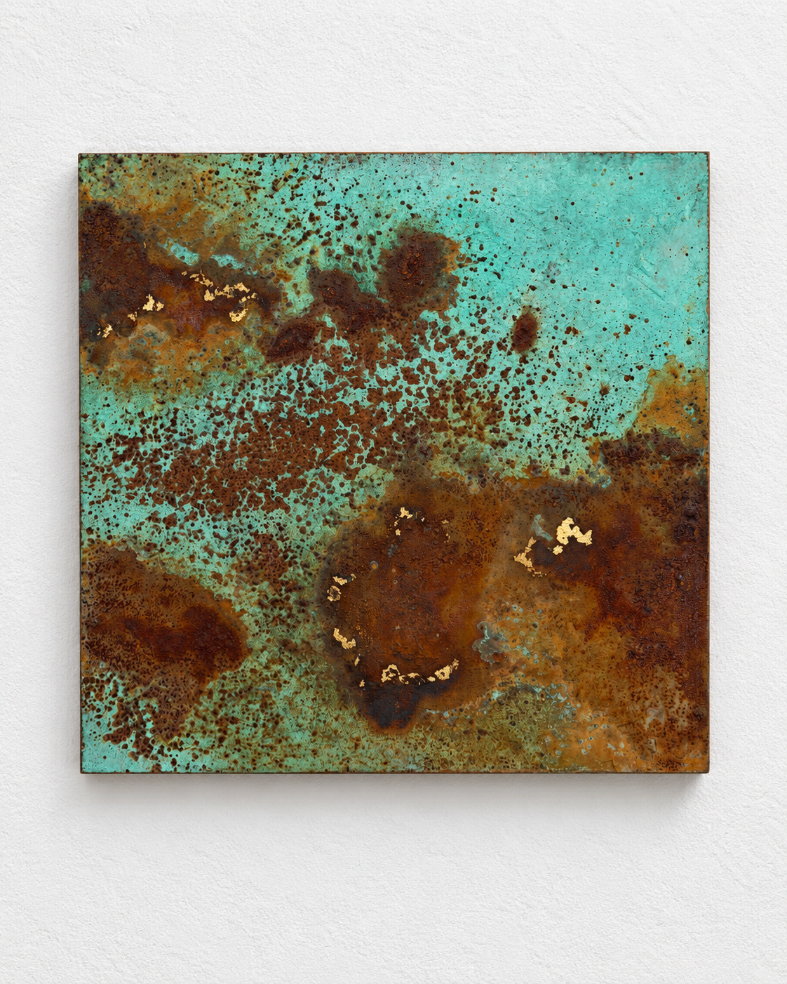 Square wall panel with turquoise verdigris and mottled rusty brown areas on a white wall.