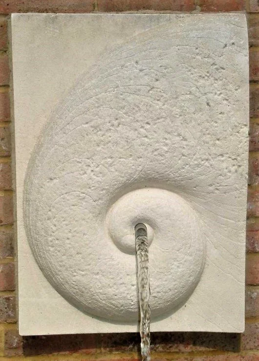 Battersea Shellmoon 2 Water Feature mounted on brick, with water flowing from the spiral centre.