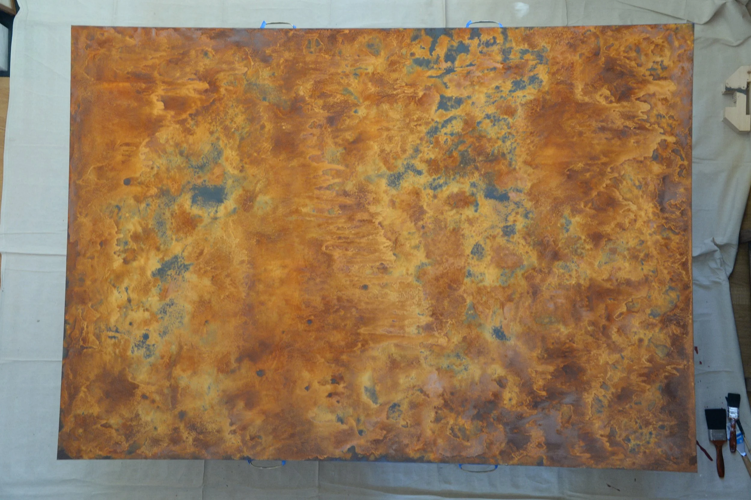 Wide textured panel with mottled rust, ochre and blue areas, photographed horizontally in the workshop.