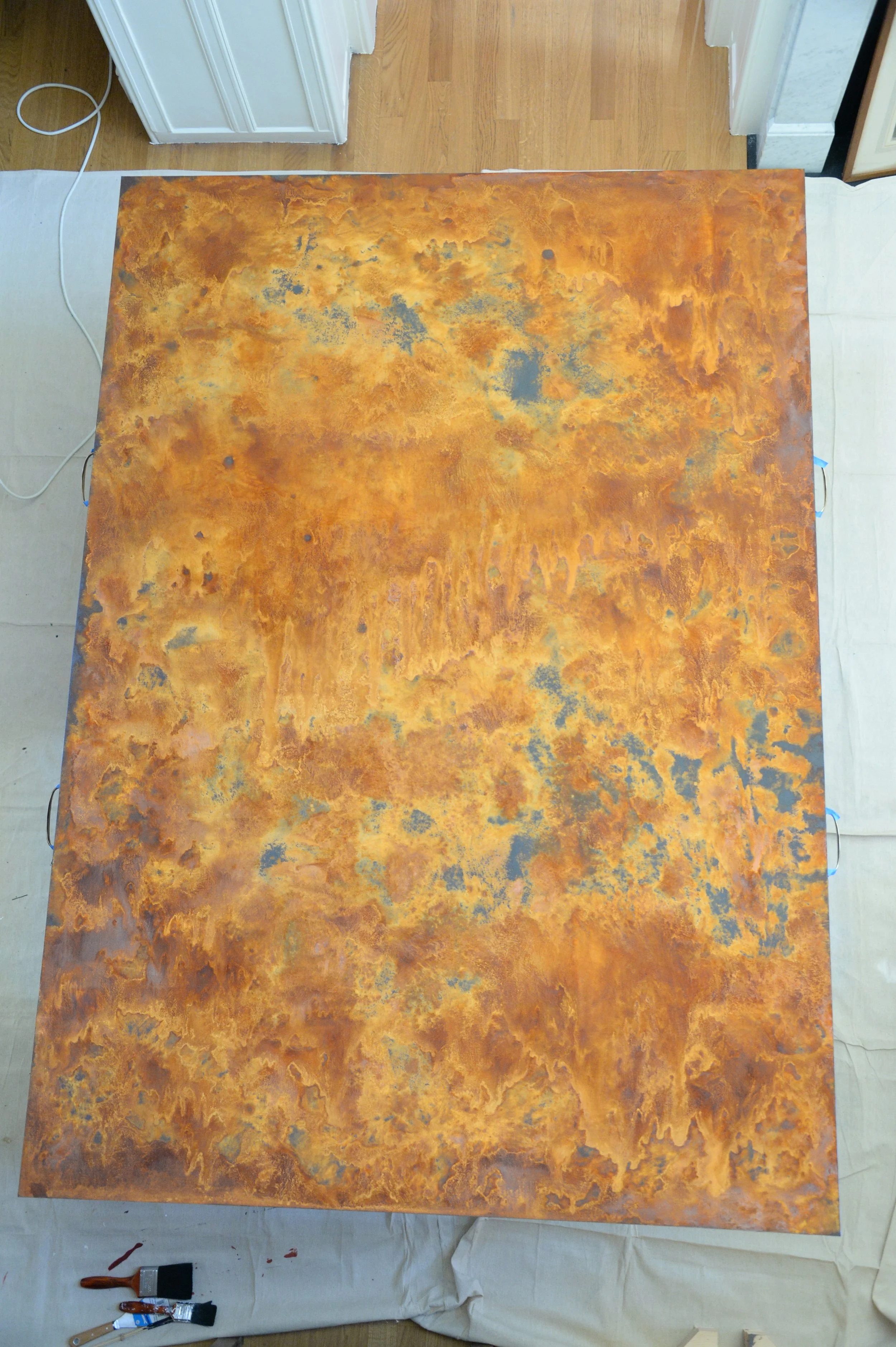Wide textured panel with mottled rust, ochre and blue areas, photographed vertically in the workshop.