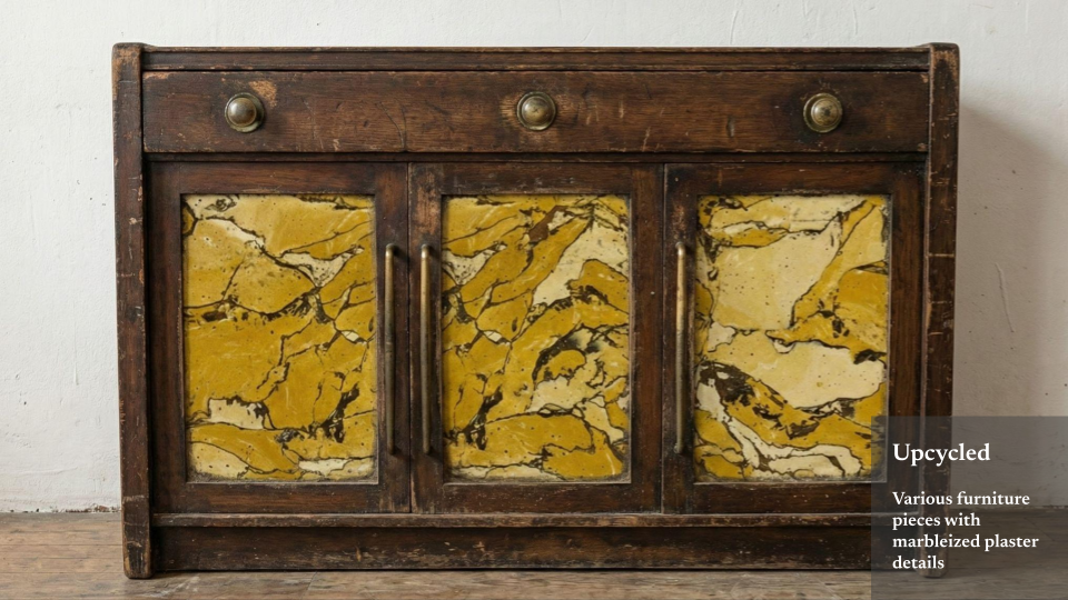 Upcycled wooden cabinet with three marbleized plaster panel doors and three small drawers on top, set against a white wall.