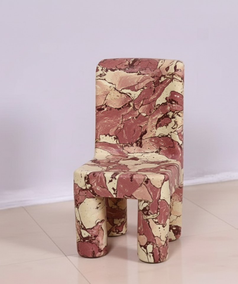 A small chair with a marble-like pattern in red, pink, cream, and black colors, standing on a beige tiled floor against a plain white wall.