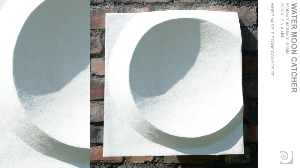 A white square-shaped textured stone sculpture with a large circular hole, placed against a brick wall, with a shadow cast inside the circle.