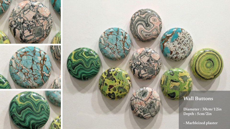 Collection of ten colorful wall buttons with marbled and patterned designs arranged on a white wall.