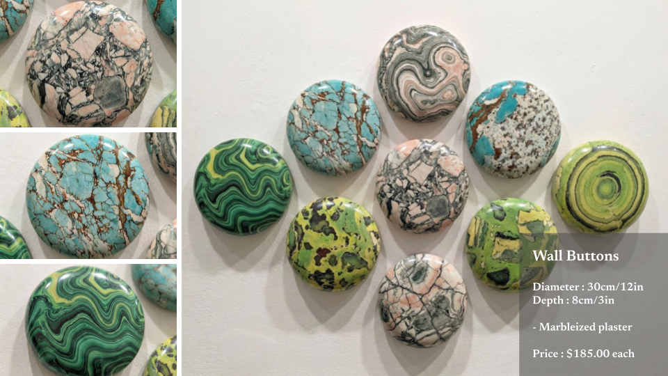 Decorative wall buttons resembling polished stones in various colors and patterns, mounted on a white wall, with a label describing size, material, and price.
