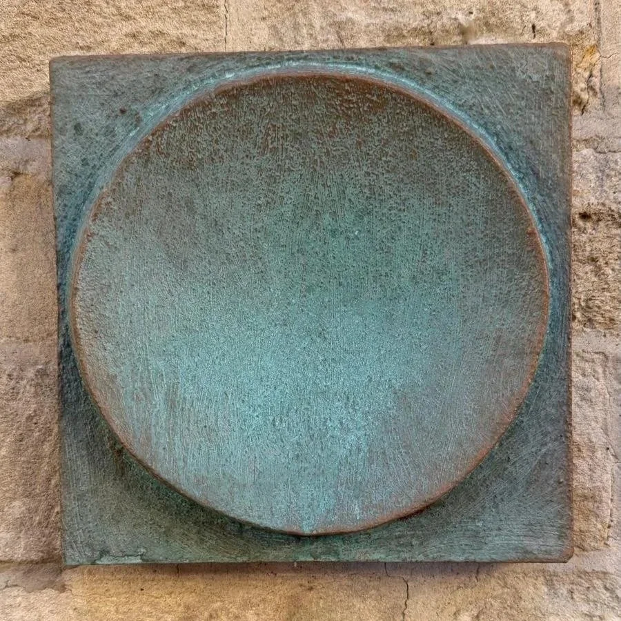 Spherical Verdigris wall sculpture, a square panel holding a domed disc in a green verdigris finish on stone