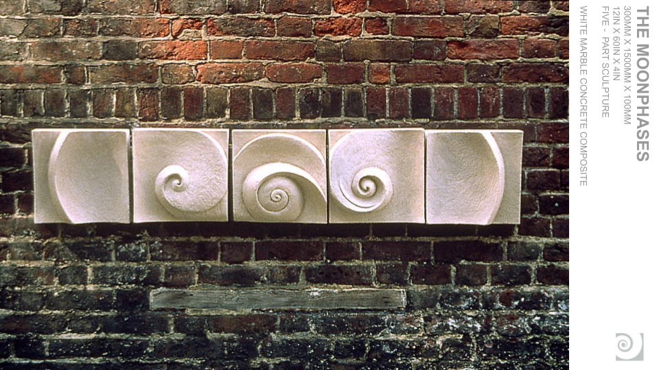Five white marble cubes with carved spiral patterns, mounted on a dark brick wall, arranged in a row.