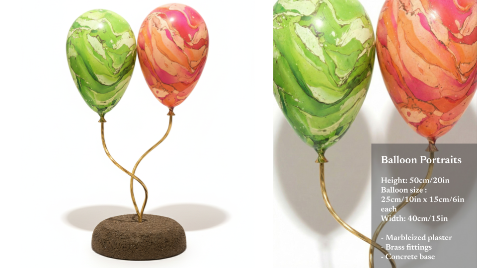 Two marbled-pattern balloons, one green and one pink, mounted on a decorative stand with a stone base and brass fittings.