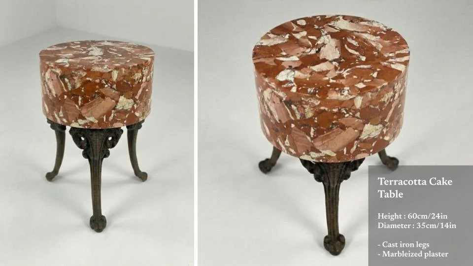 A small table with a terracotta cake-like marbleized top and cast iron legs.