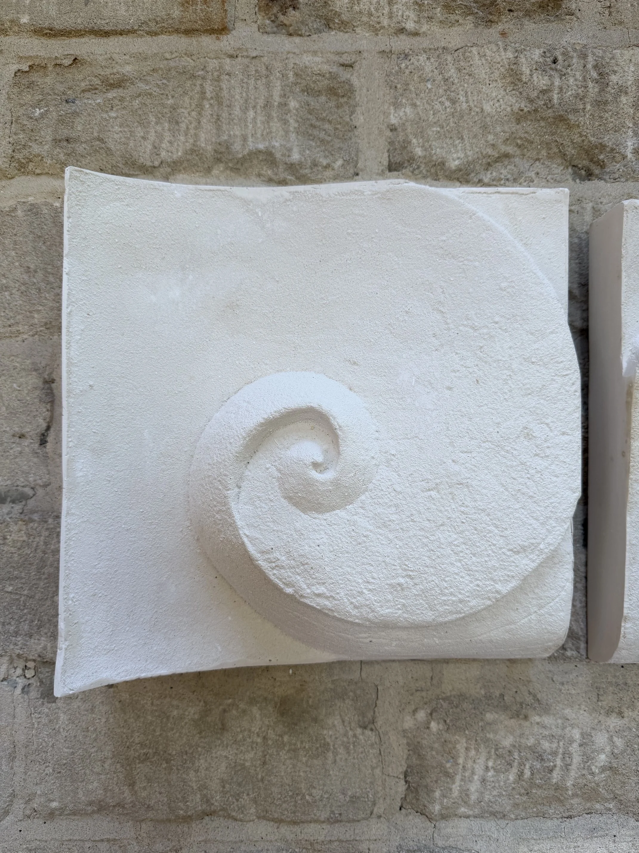 Wave Phase White Wall Sculpture, a single white panel carved with a curling wave spiral
