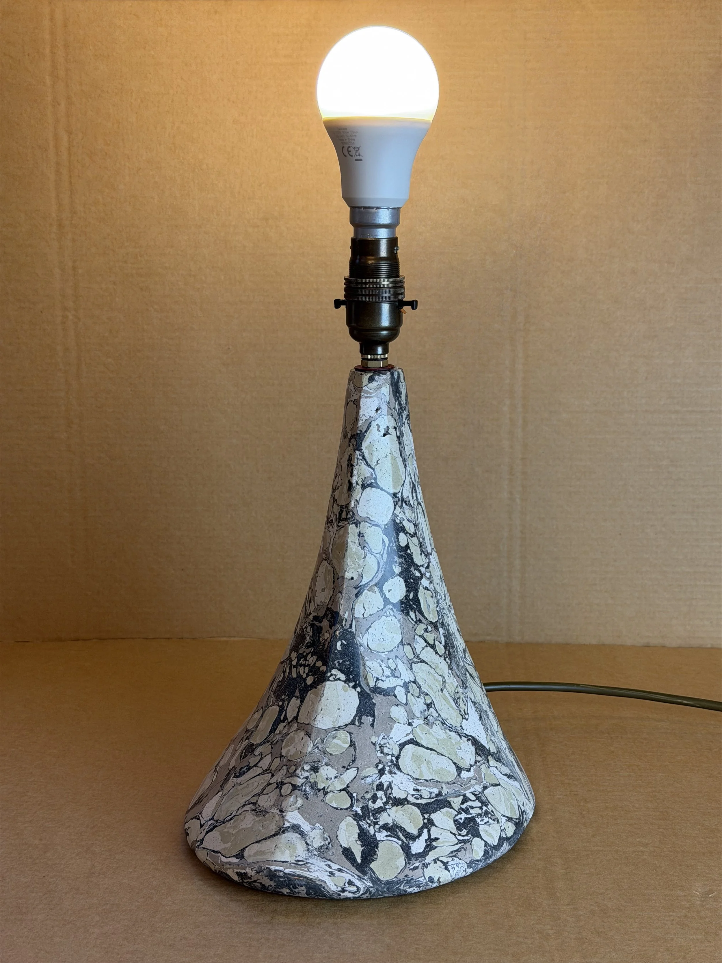 Green and Cream Lamp base fitted with a bulb and lit, without a shade