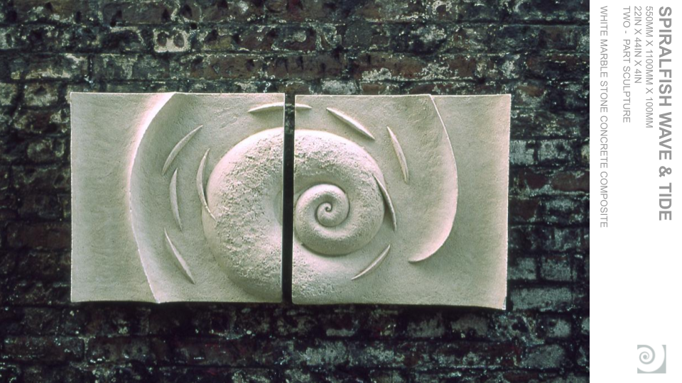 Two marble sculptures with a spiral shell design against a brick wall background.