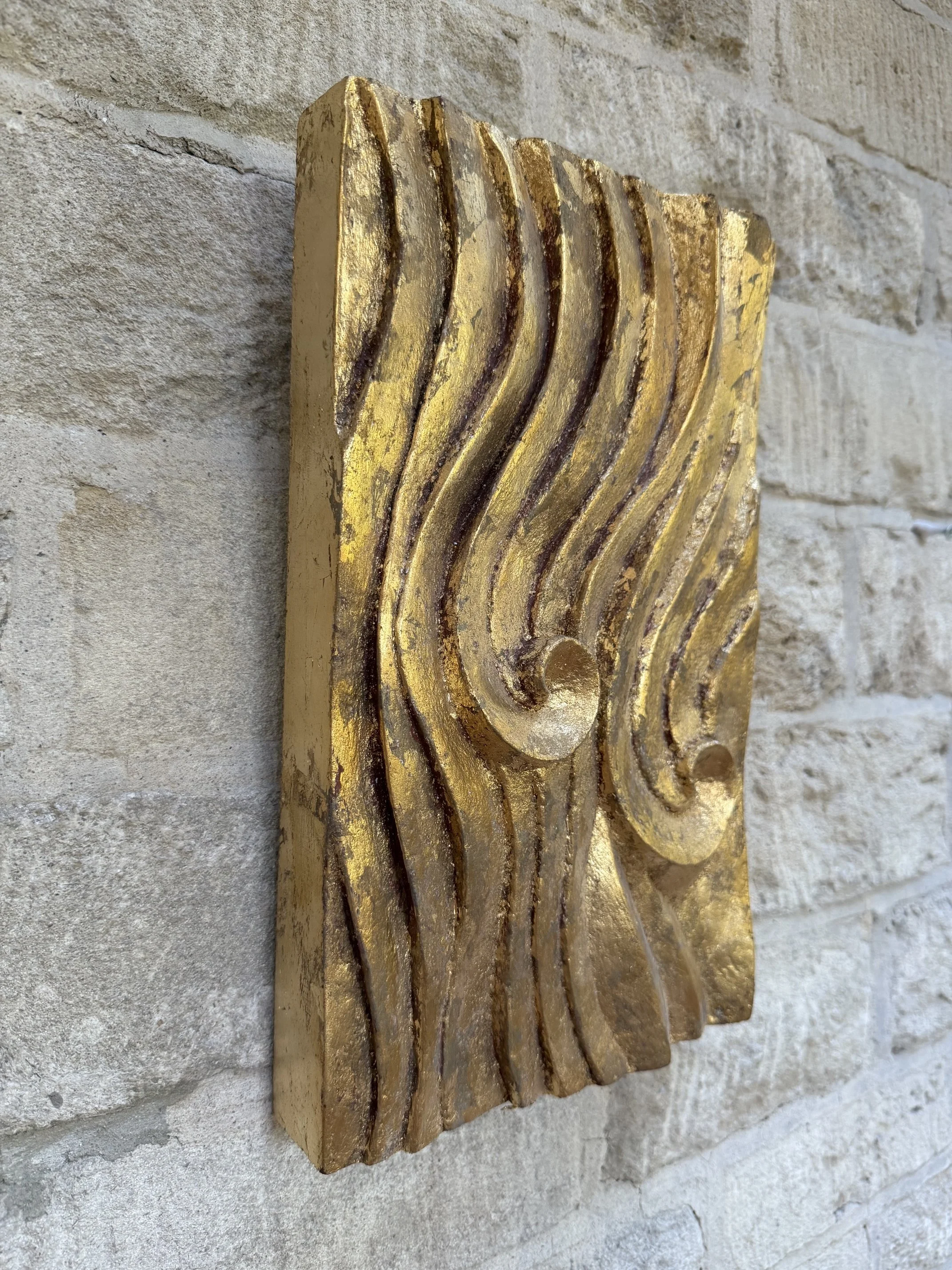 Gold-Leaf Wave Relief Sculpture seen at an angle, the gilded wave crests catching the light