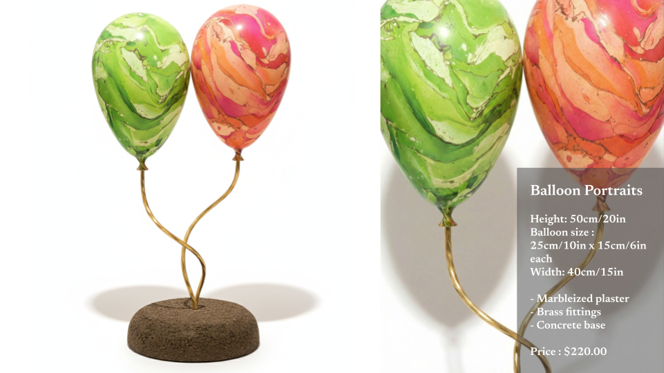 Two marbleized painted balloons with gold-colored strings attached to a concrete base, displayed as balloon portraits.