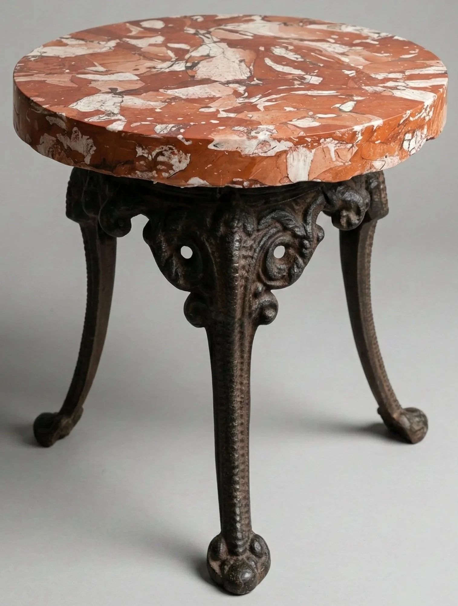 Terracotta Top Accent Table with metal legs, a round terracotta and cream marbled top on cast legs