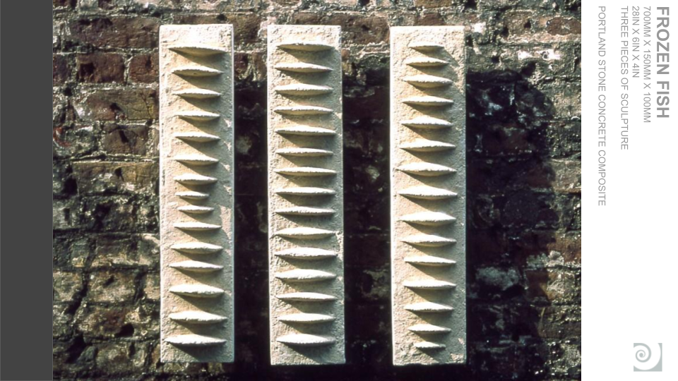 Three elongated white sculptures with pointed, cone-shaped protrusions, mounted on a brick wall.