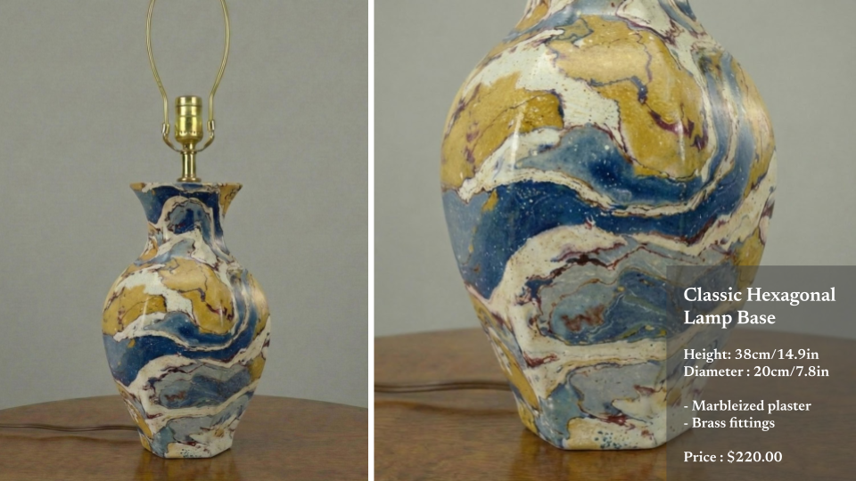 A vintage-style table lamp with a marbleized plaster hexagonal base featuring swirling blue, gold, white, and burgundy colors, fitted with brass fittings. The lamp has a brass socket and a brass harp for the lampshade. The background is neutral, and 