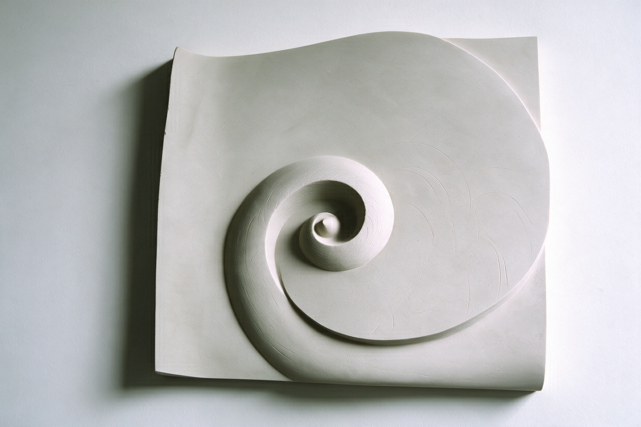 Front view of the Barbados Wave sculpture showing the deep spiral scroll and the curled upper edge of the panel