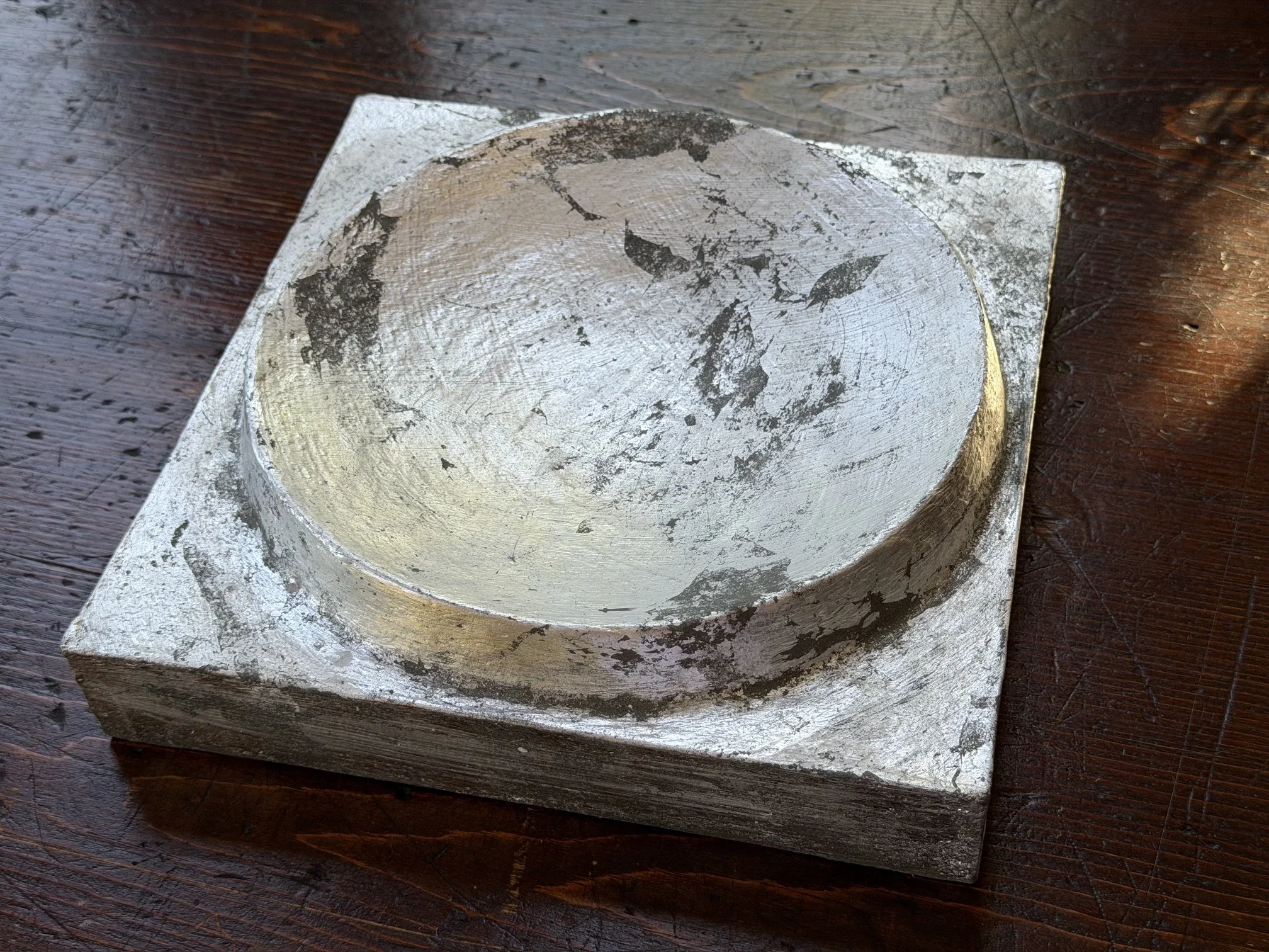 Silver and Bronze on Concave Moon resting on a dark wooden table, seen from above