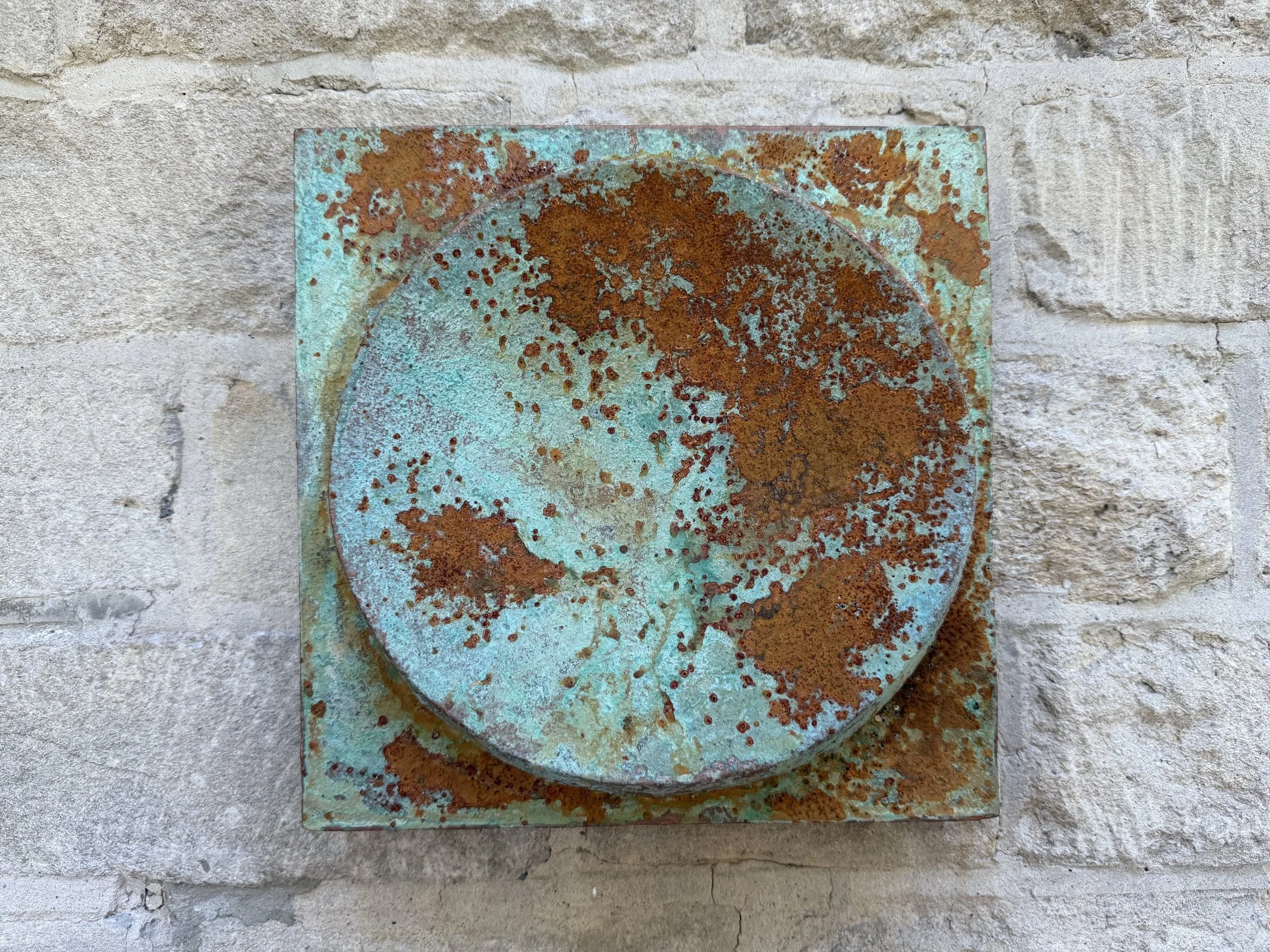 Moon Crater Phase Copper Verdigris Wall Sculpture seen square on, rust blooming across the verdigris crater