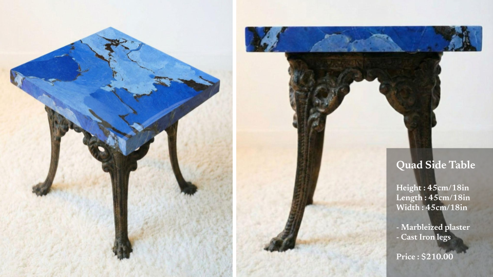 A small side table with a blue marble top and cast iron legs with ornate design.