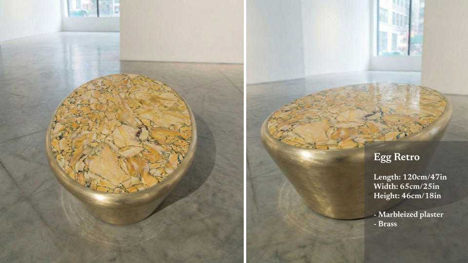 A retro-style bench with a brass base and a marble top resembling an egg, set in a bright, minimalist gallery with large windows.