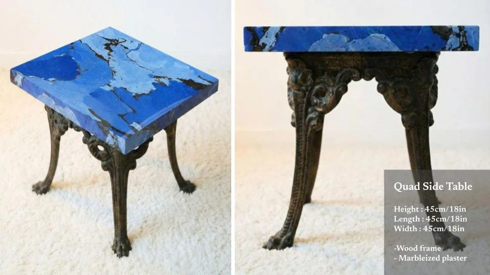 Side view of a small, decorative quad side table with a blue marbled plaster top and an ornate wooden frame with carved legs resembling animal paws.