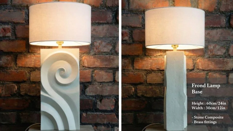 Two decorative lamps with ceramic bases, each with a spiral or textured design, placed against a brick wall. The left lamp has a swirling pattern, and the right lamp has a wavy design. Both have white drum shades. The right lamp's base details are ov