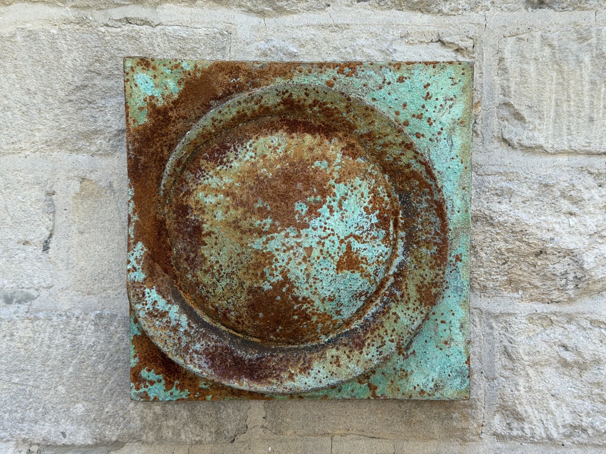 Moon Crater Phase Verdigris Spherical Wall Sculpture, a rusted crater disc on a verdigris panel on stone