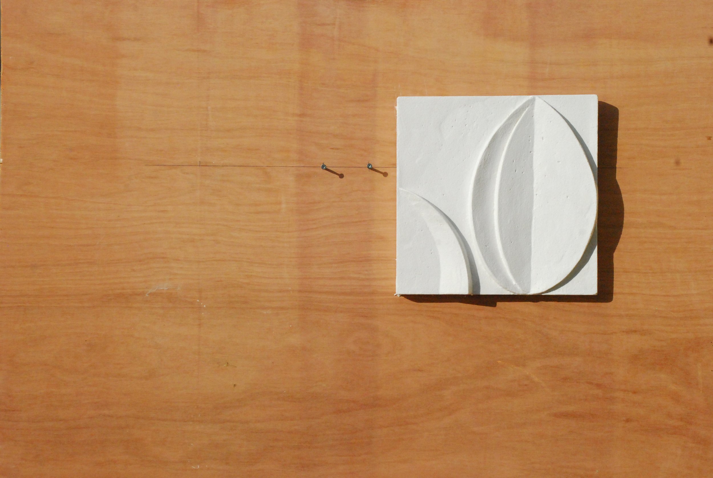 Angled view of the white acanthus flower wall sculpture showing the depth and shadow of the carved relief