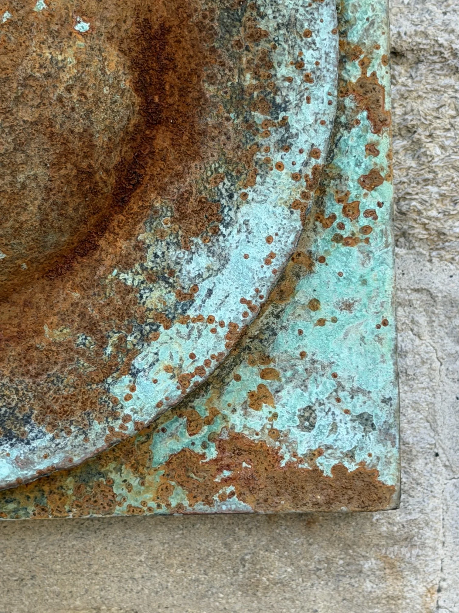 Detail of the Moon Crater Verdigris Rust Wall Sculpture showing the crater rim against the stone wall