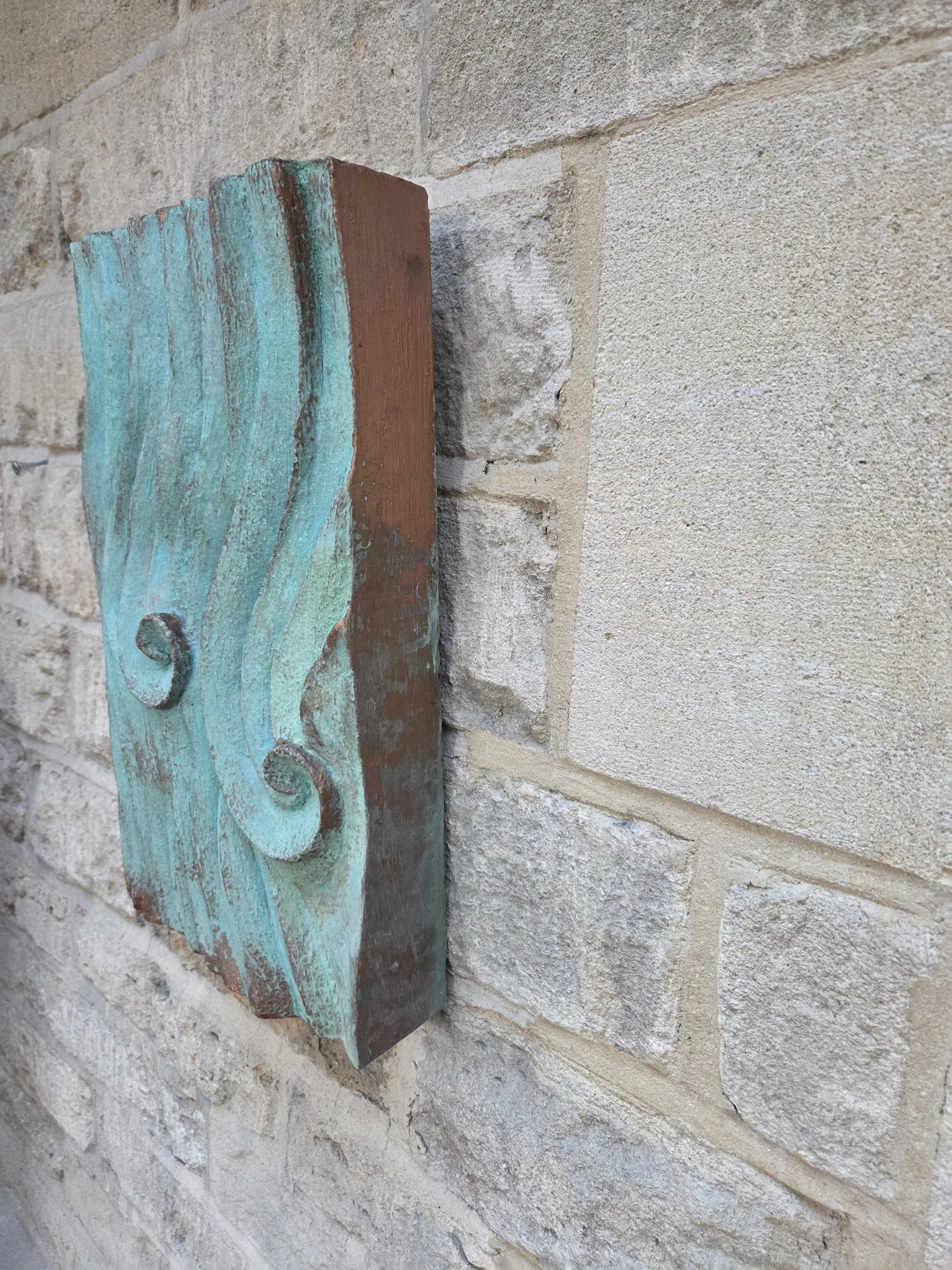 Wave Relief Wall Sculpture in verdigris viewed from the side, showing the panel edge against stone