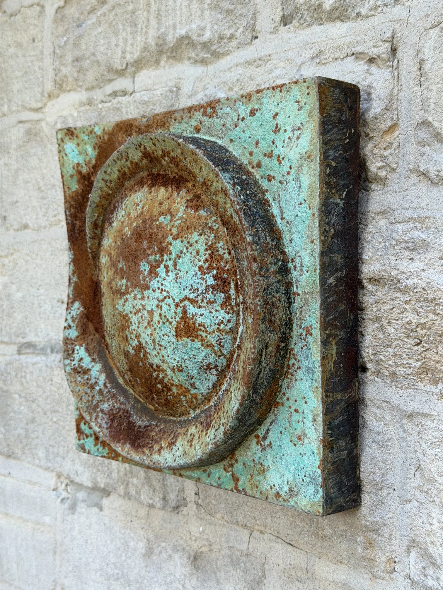 Moon Crater Phase Verdigris Spherical Wall Sculpture seen in profile, the panel projecting from the stone wall
