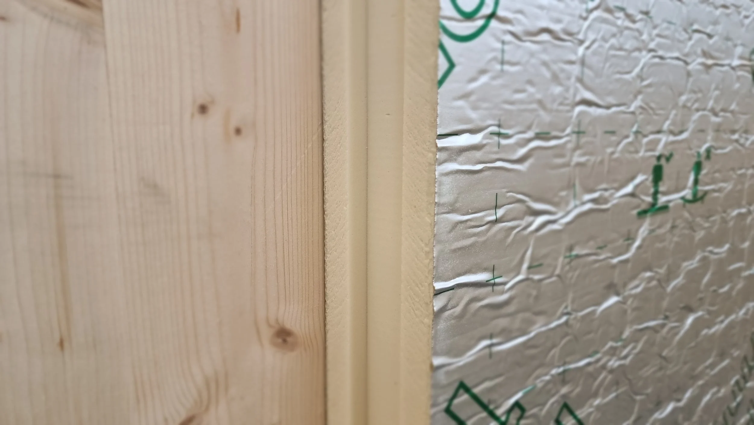 Close-up of wooden wall and siding with insulation material between.