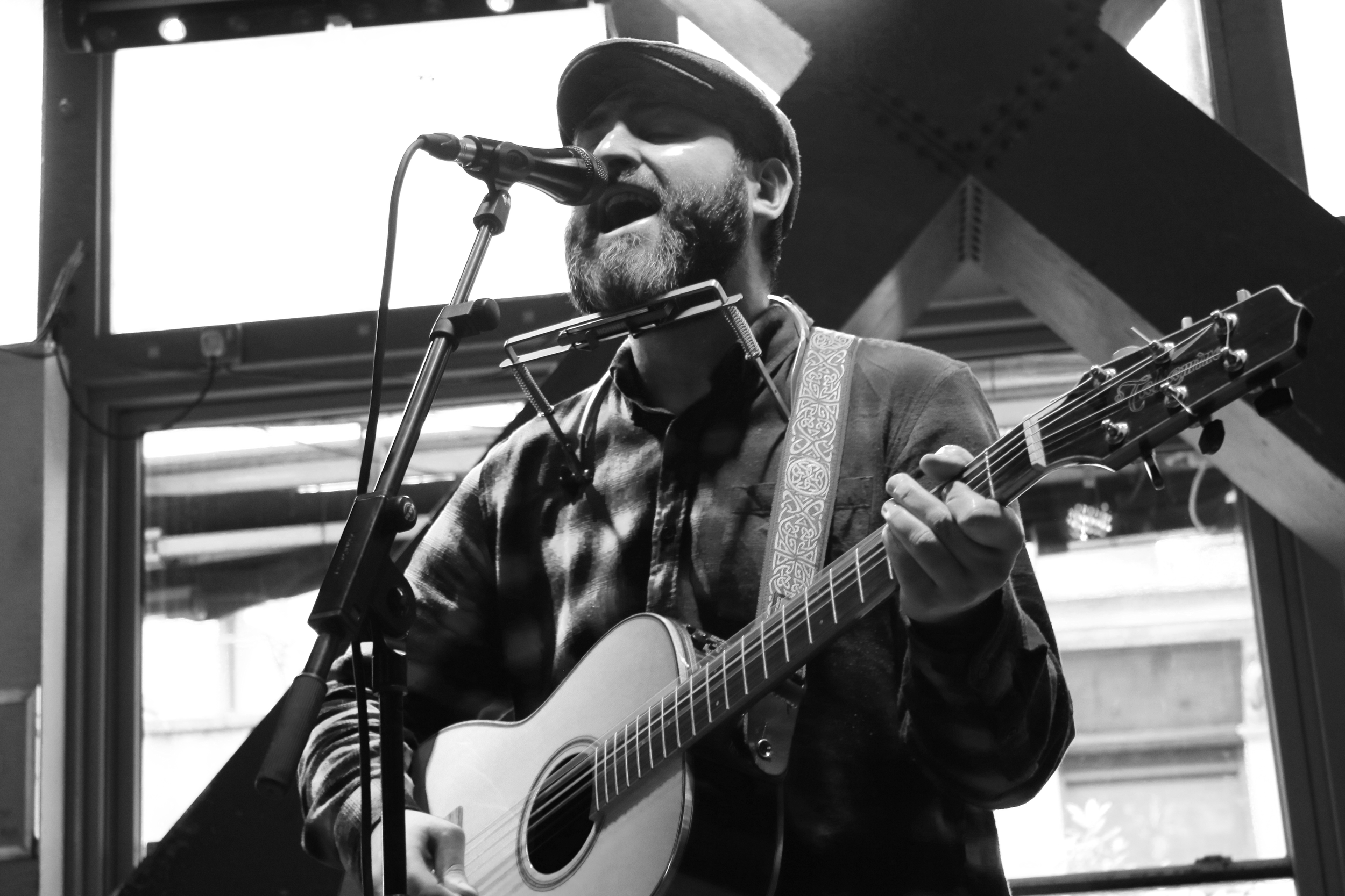 Black and white image of Adam Sherry performing on stage singing into a microphone