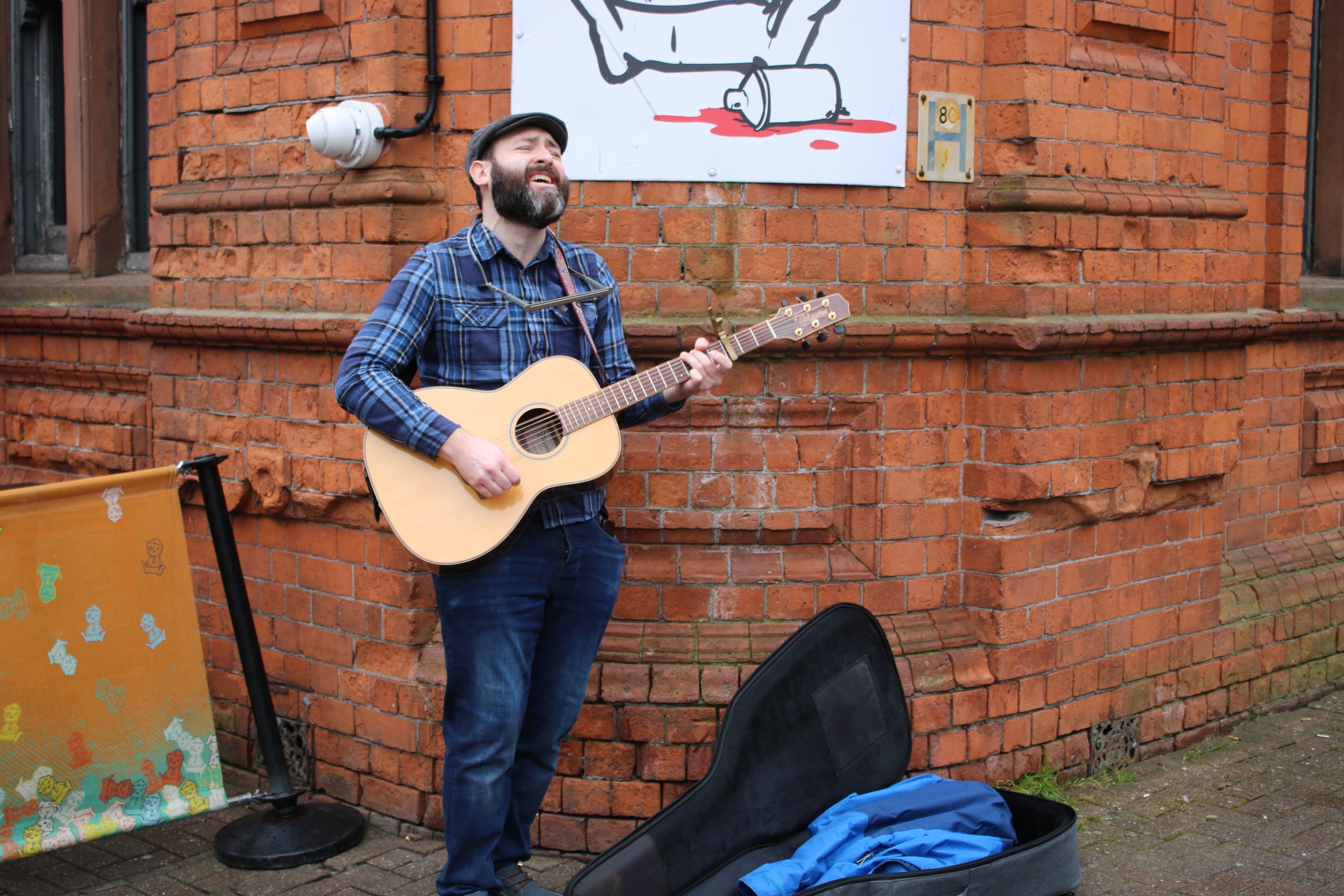 Image of Adam Sherry busking on the street with his guitar