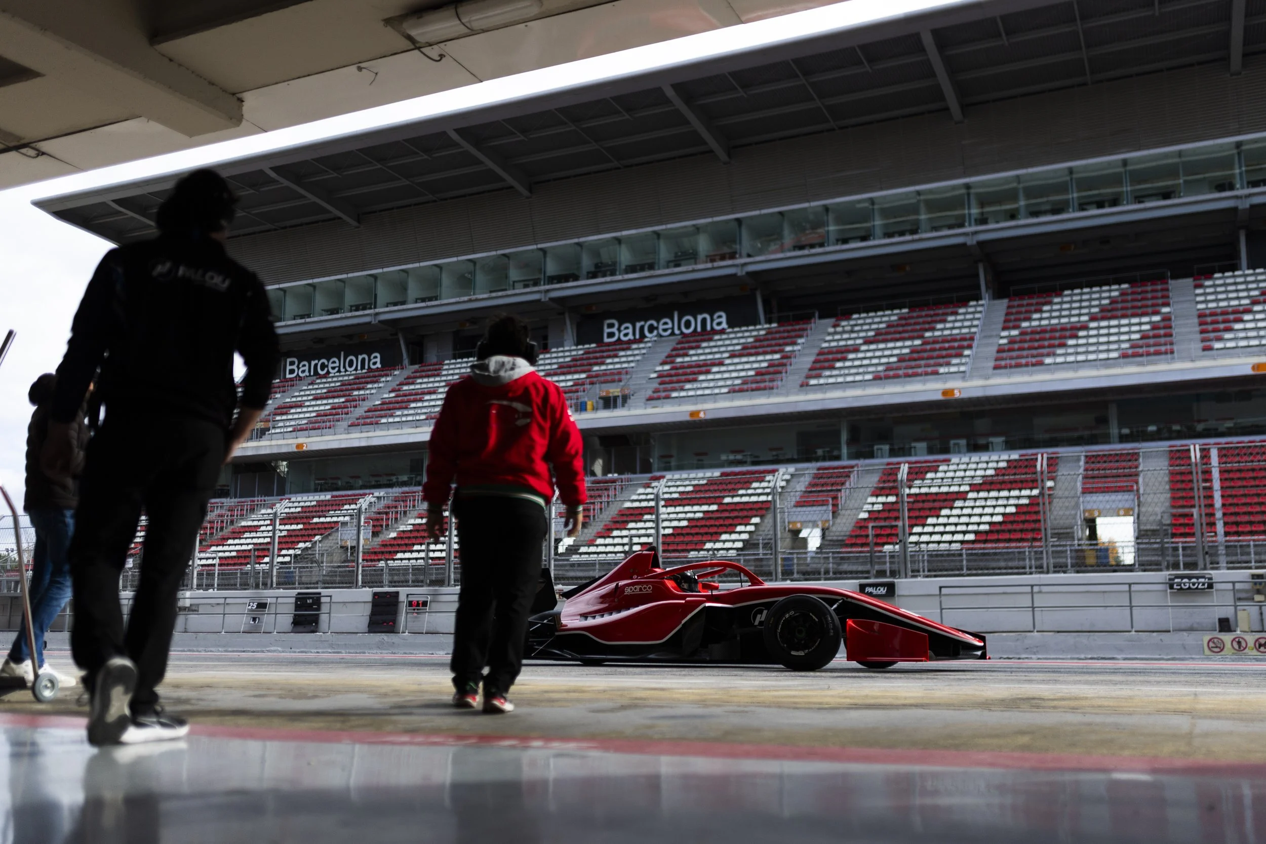 Persona en un garaje de carreras observando un auto de carreras en la pista en el circuito de Barcelona.