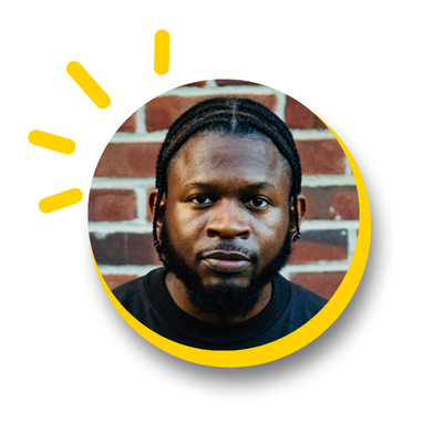 Photo in the shape of a circle with a close up of man standing in front of a red brick wall. The circle has a sliver of yellow around the right side and a starburst effect on the left
