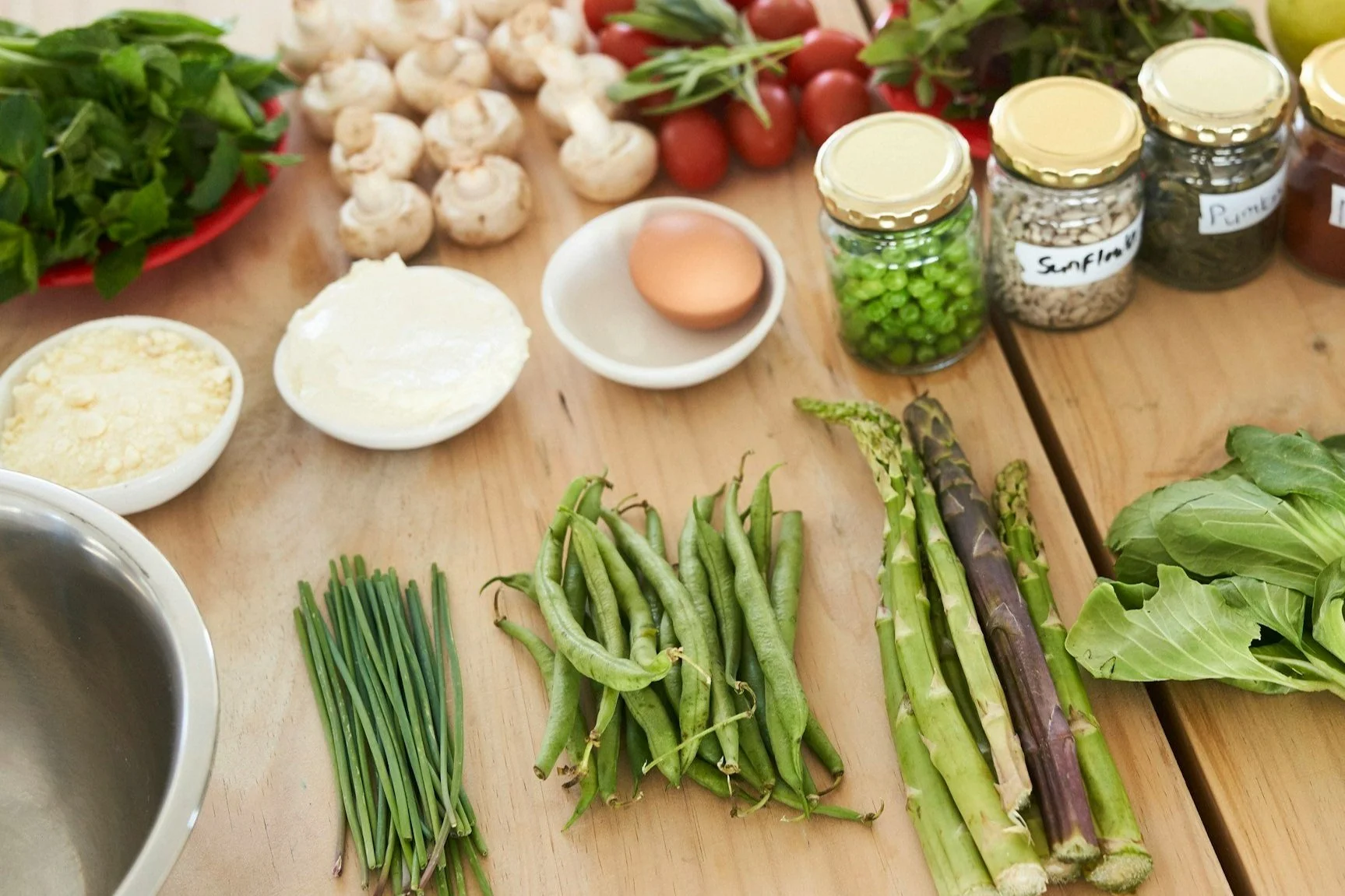 Assortment of green vegetables such as peas, asparagus, and lettuce on a wooden table.