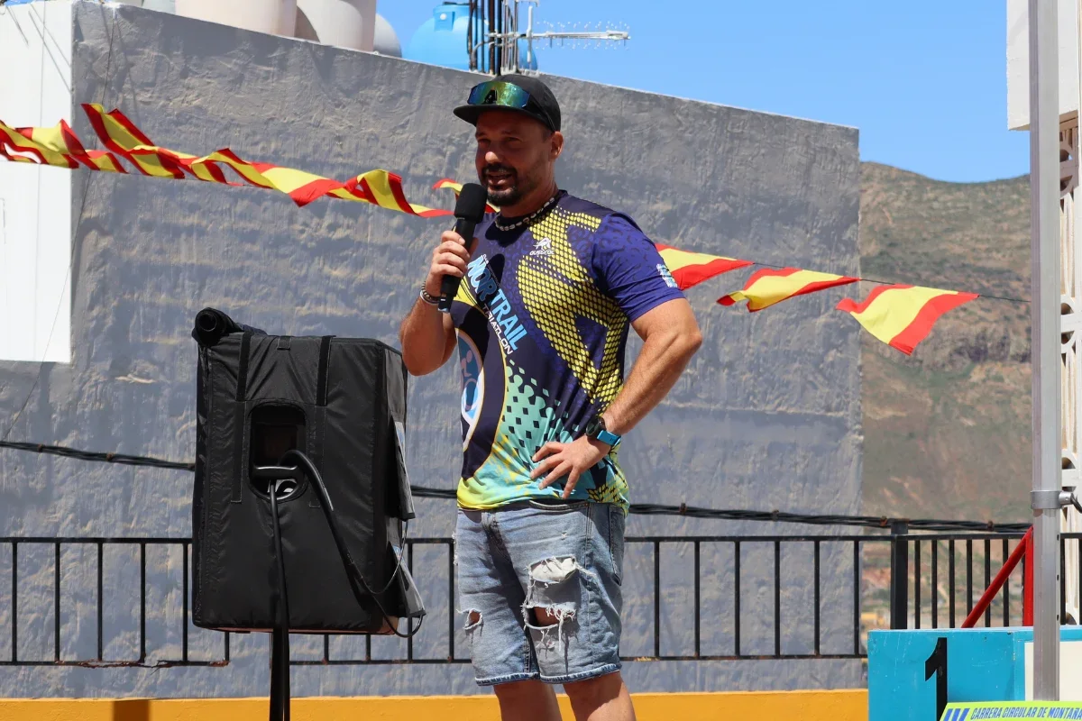 Tito, organizador de la Carrera Solidaria Santa Rita, hablando con micrófono durante una edición de la prueba en Anzo de Guía