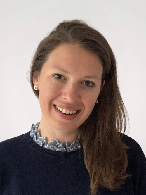 Smiling woman with brown hair, wearing a navy jumper.