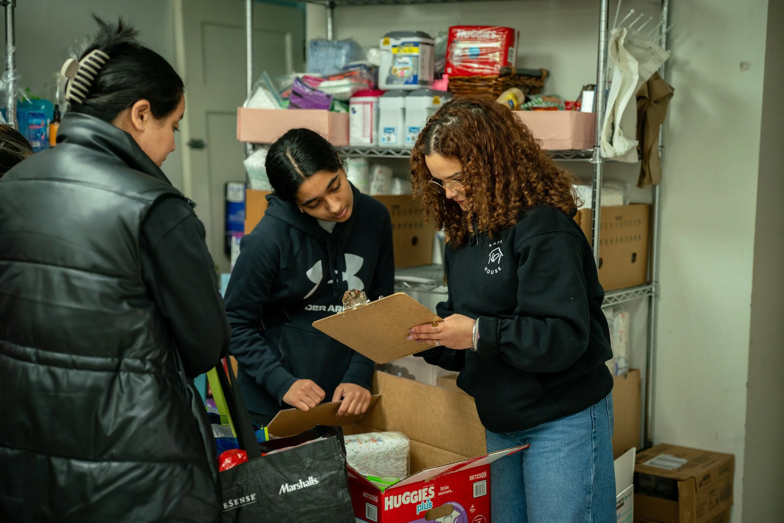 Volunteer handing a bag of groceries to a family at Raphael House in Langley BC