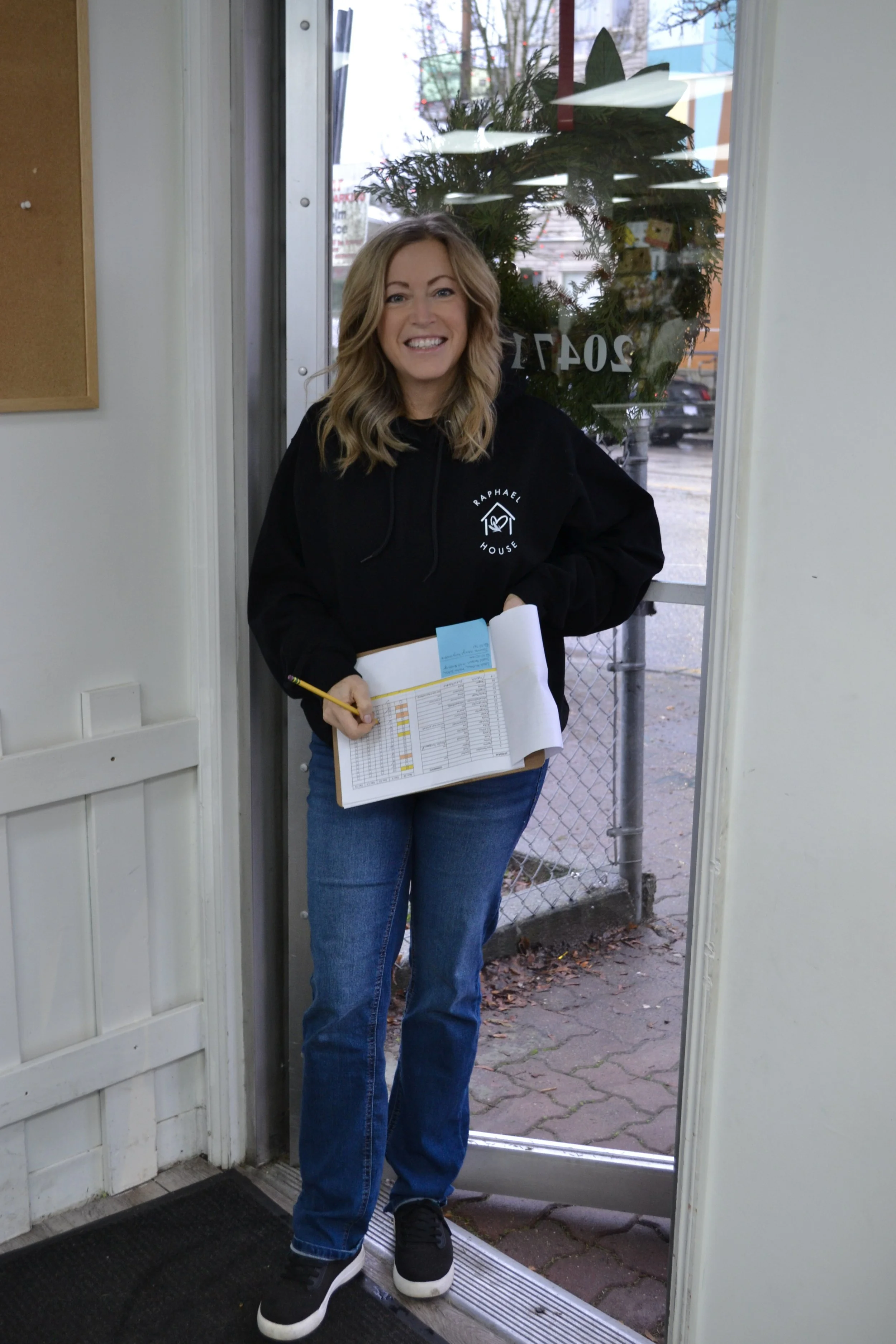 Raphael House volunteer welcoming a family at food pickup in Langley