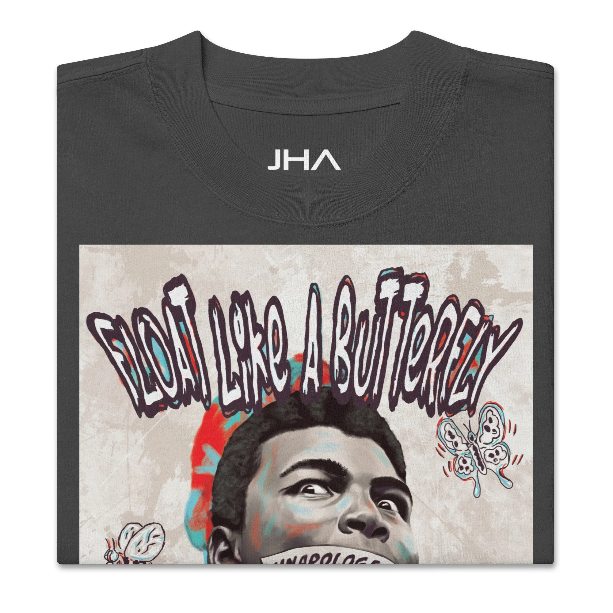 Folded oversized faded black T-shirt with a Muhammad Ali graphic, featuring 'Float like a butterfly' text and symbolic imagery