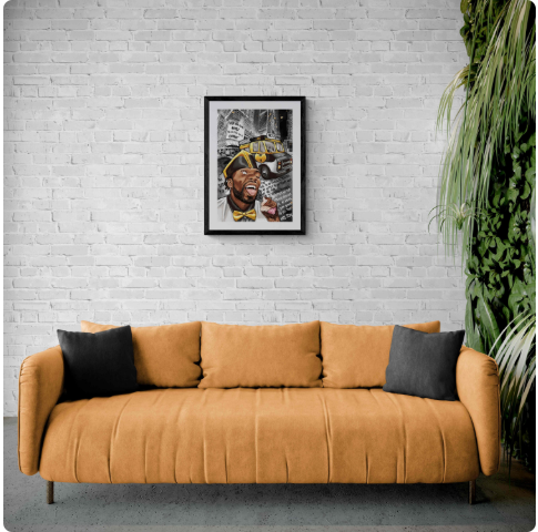 Framed artwork above tan sofa against white brick wall with green plant decor.