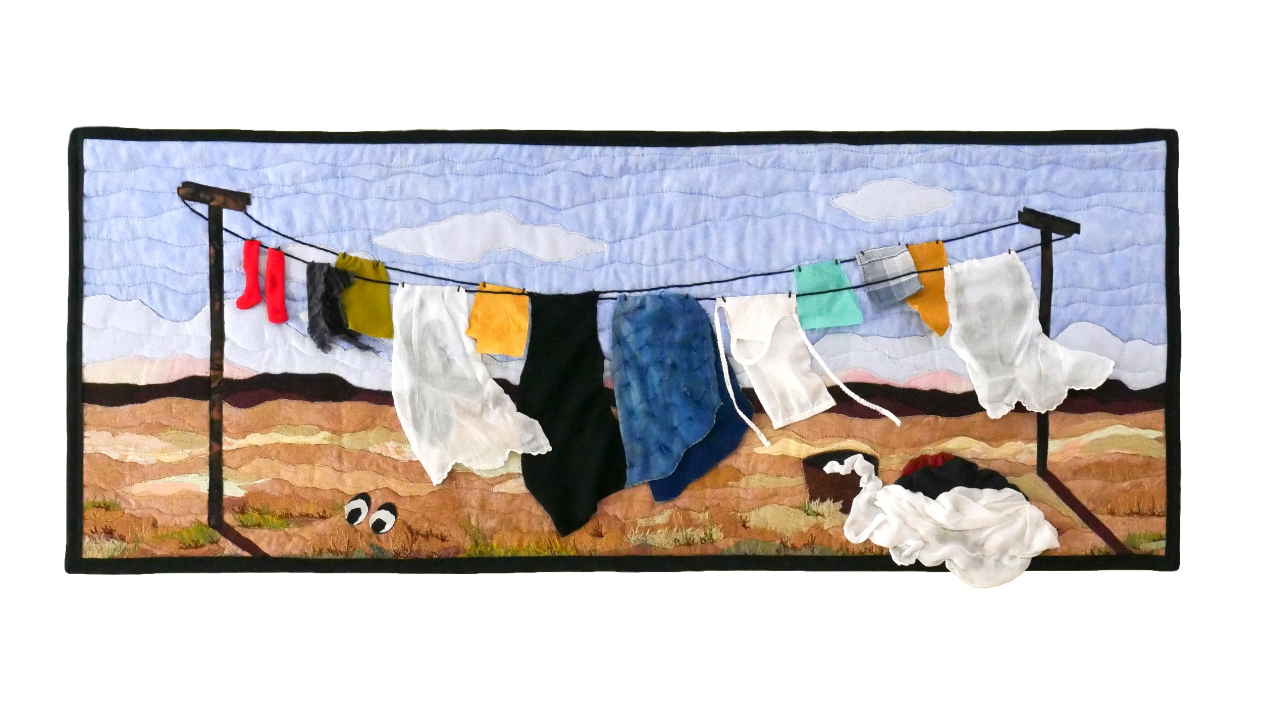 Quilt of a clothesline covered in colorful clothes set against a desert backdrop with mountains in the distance