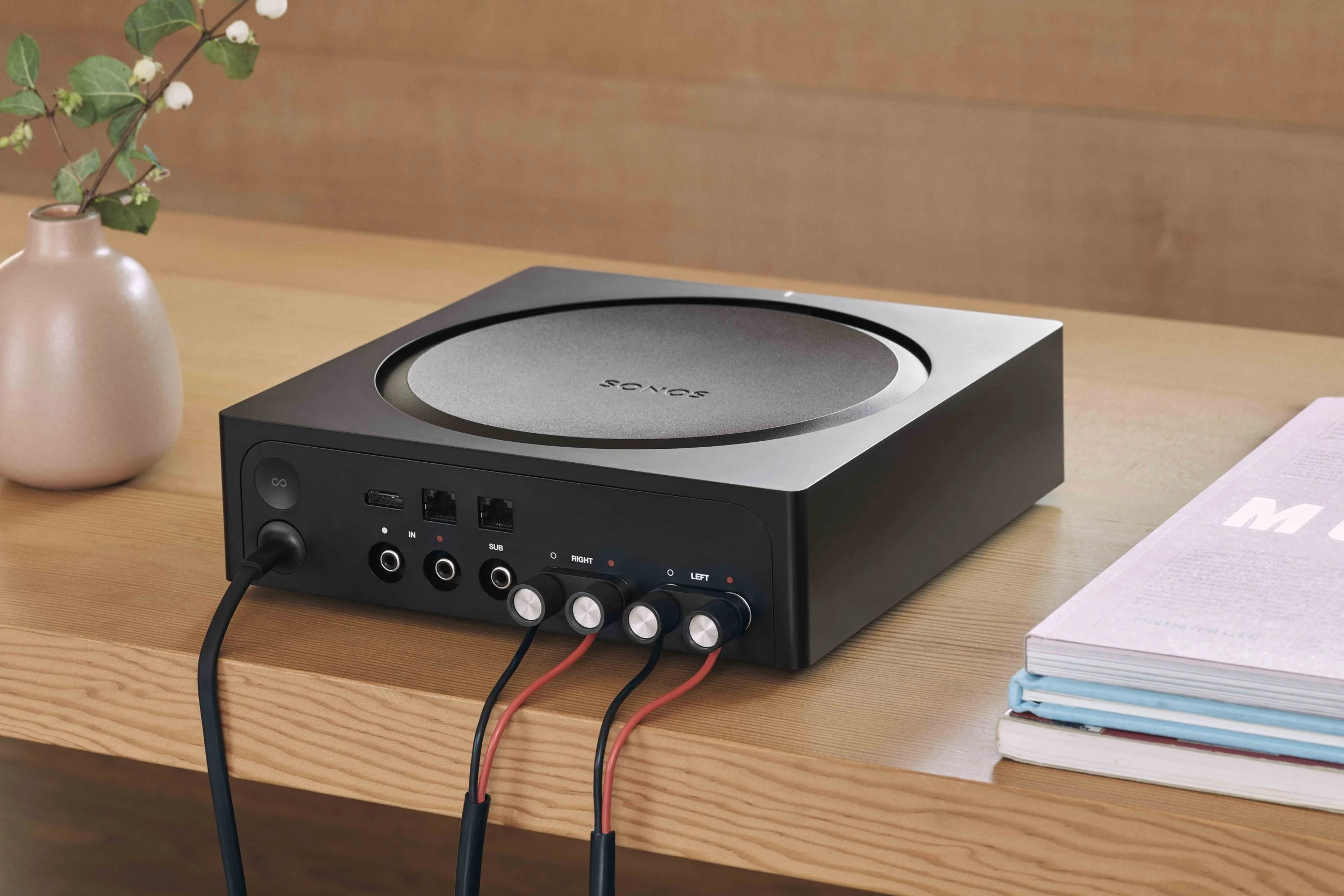 The rear wiring connections of a black Sonos Amp sitting on a wooden table. As an Authorized Sonos Dealer, Katabatic Connections provides professional audio wiring and custom home sound system installations in Livingston, Bozeman and Southwest MT.